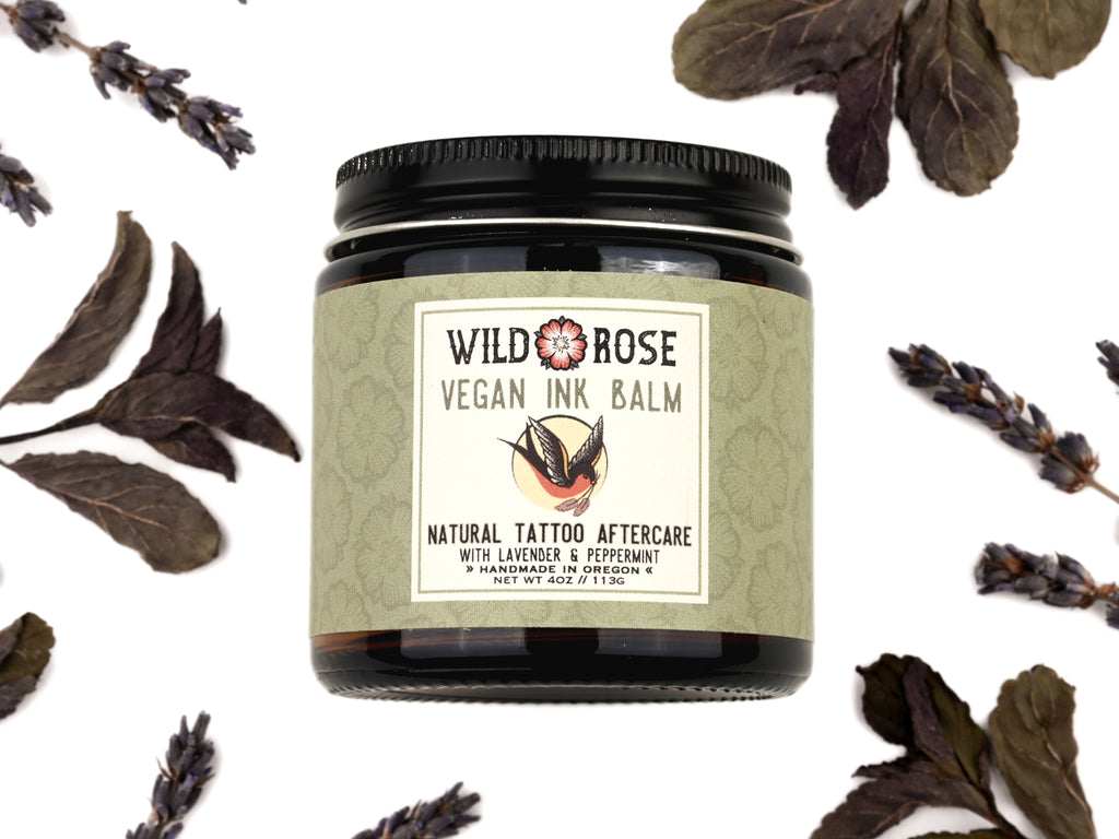 Vegan Ink Balm Natural Tattoo Aftercare in a 4oz amber glass jar with metal lid. Dried lavender and peppermint surround.