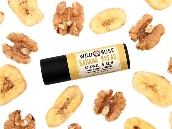 Banana Bread Natural Lip Balm in biodegradable paper tube. Dried bananas and walnuts surround.