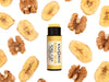 Banana Bread Natural Lip Balm in biodegradable paper tube. Cap is off revealing a creamy yellow lip balm. Dried bananas and walnuts surround.