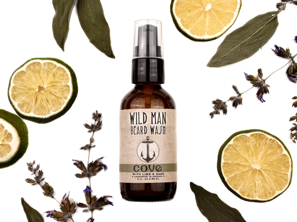 Wild Man Beard Wash Cove scent in 2oz amber bottle. Lime slices and sage leaves surround.