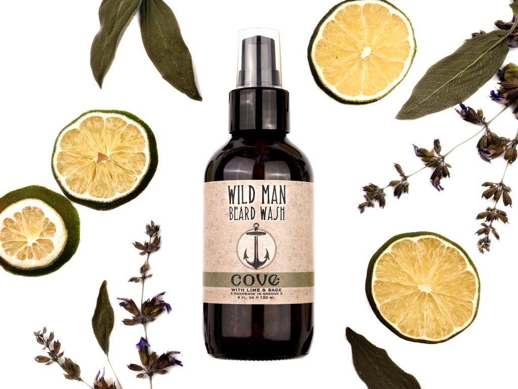 Wild Man Beard Wash Cove scent in 4oz amber bottle. Lime slices and sage leaves surround.