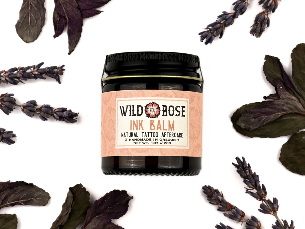 Ink Balm Natural Tattoo Aftercare in a 1oz amber glass jar with metal lid. Dried lavender and peppermint surround.