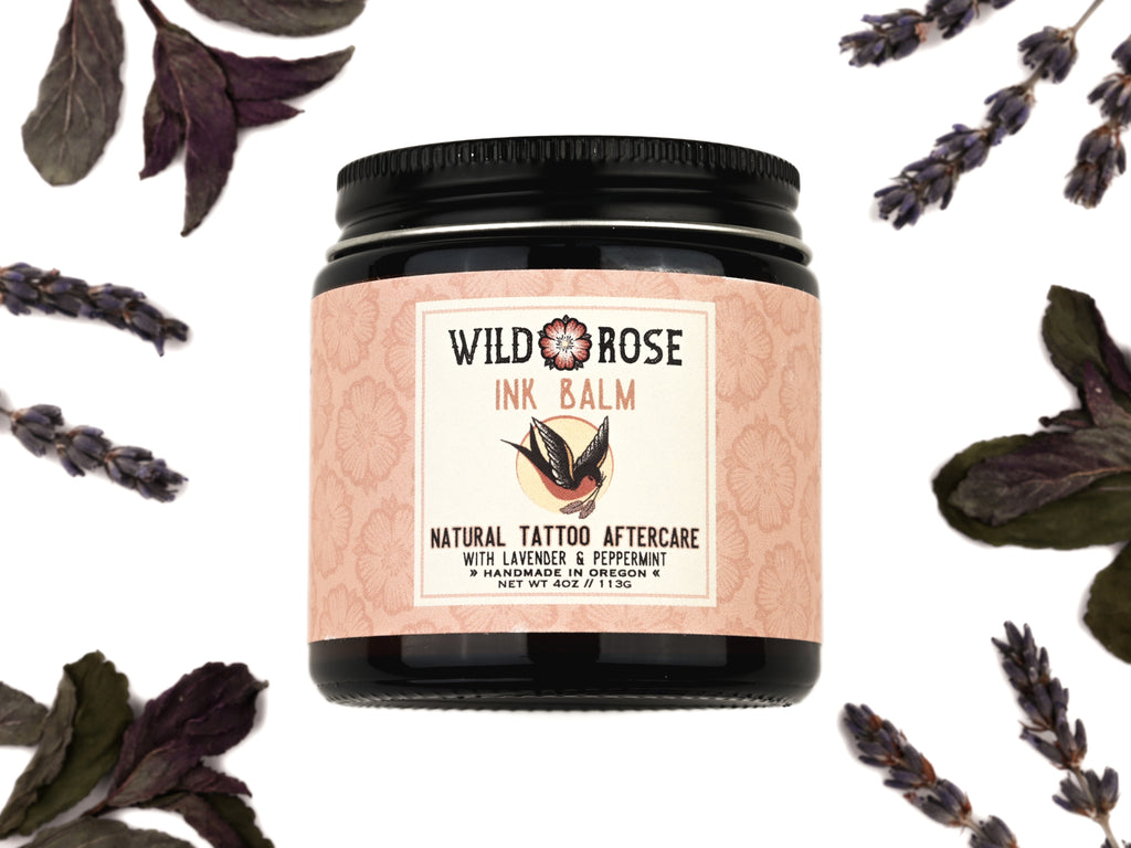 Ink Balm Natural Tattoo Aftercare in a 4oz amber glass jar with metal lid. Dried lavender and peppermint surround.