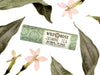 Jasmine Tea Natural Lip Balm in a biodegradable paper tube. Dried leaves and pressed flowers surround.