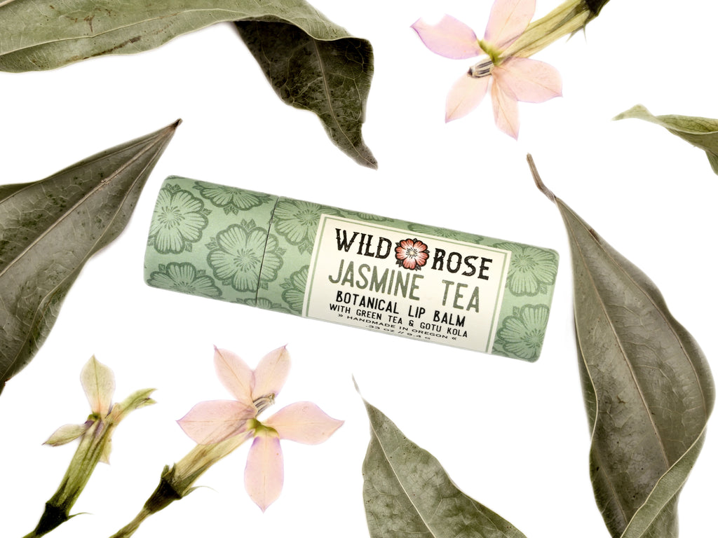 Jasmine Tea Natural Lip Balm in a biodegradable paper tube. Dried leaves and pressed flowers surround.