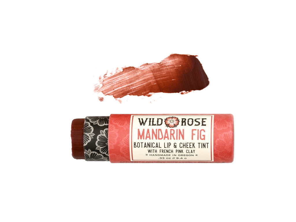 Wild Rose Mandarin Fig Botanical Lip & Cheek Tint in a biodegradable tube on a white background. The cap is removed revealing a dark red creamy tinted balm.  A color swatch is above.