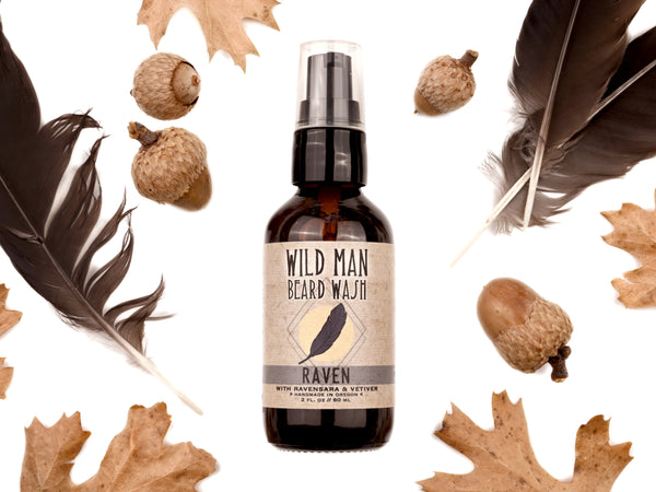 Wild Man Beard Wash - Raven scent in 2oz amber glass bottle. Black feathers, acorns and dried oak leaves surround. 