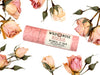 Wild Rose Rosebud Botanical Lip Balm in a biodegradable tube on a white background with dried roses surrounding. 