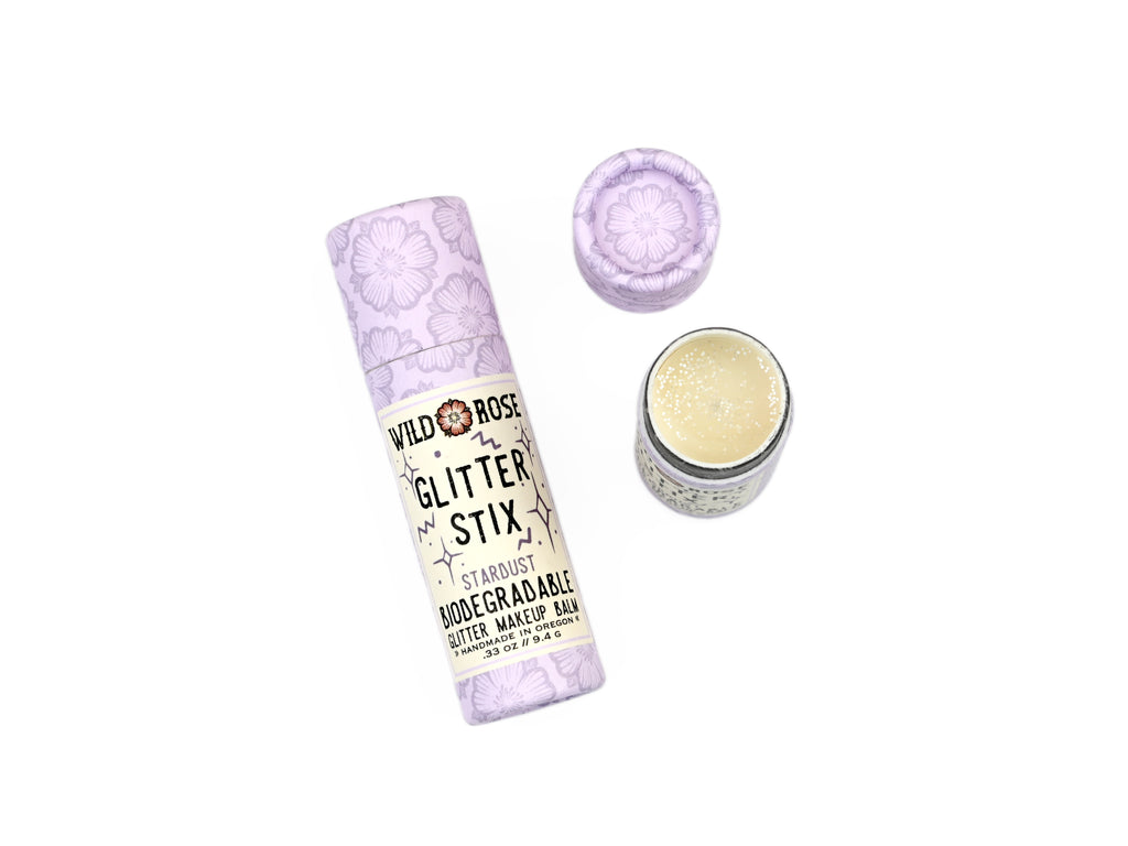 Wild Rose Biodegradable Glitter Stix makeup balm in Stardust on a white background with lid removed revealing a silver sparkly balm.