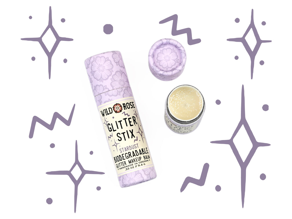 Wild Rose Biodegradable Glitter Stix makeup balm in Stardust on a white background with decorative elements.