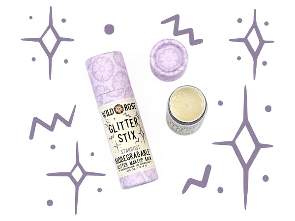 Wild Rose Biodegradable Glitter Stix makeup balm in Stardust on a white background with decorative elements.