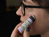 Person applying biodegradable glitter stix in Stardust to face with blurred background
