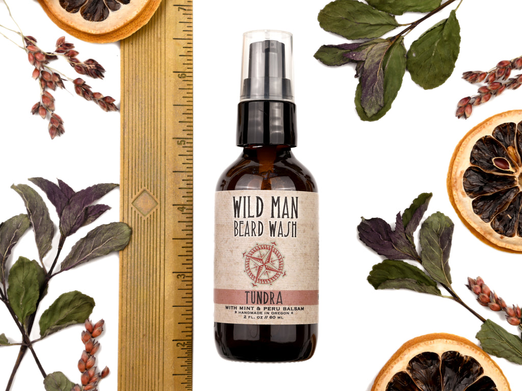 Wild Man Beard Wash Tundra scent in 2oz amber glass bottle. Shown with ruler at about 5" tall. Lemon slices and peppermint leaves surround.