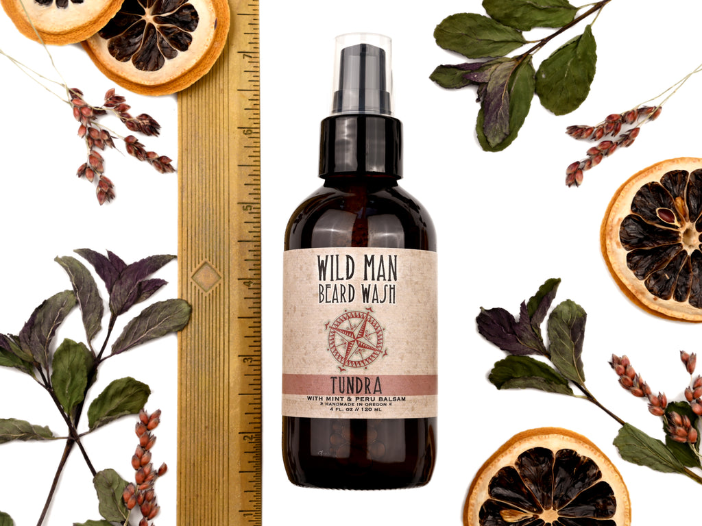 Wild Man Beard Wash Tundra scent in 4oz amber glass bottle. Shown with ruler at about 6" tall. Lemon slices and peppermint leaves surround.