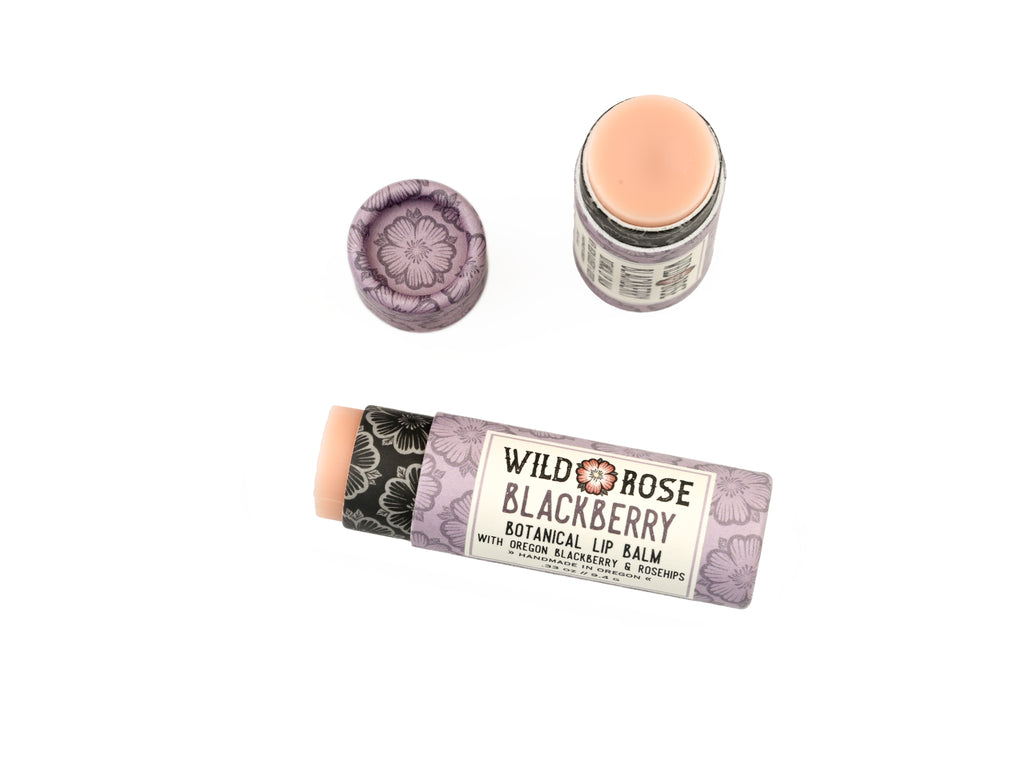 Blackberry Natural Lip Balm in a biodegradable paper tube on a white background. The cap is off revealing a creamy soft pink balm. 