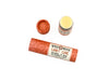 Candy Cane Natural Lip Balm in a biodegradable paper tube on a white background. The cap is removed, revealing a creamy white balm. 