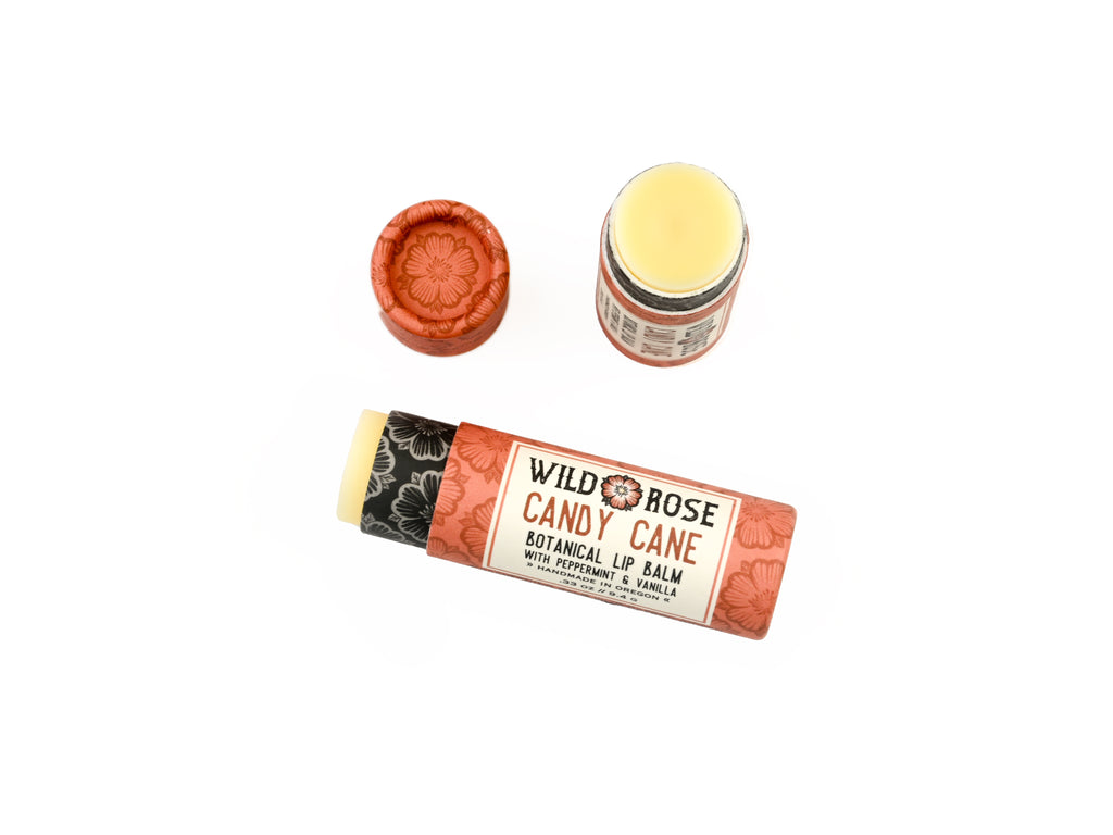 Candy Cane Natural Lip Balm in a biodegradable paper tube on a white background. The cap is removed, revealing a creamy white balm. 