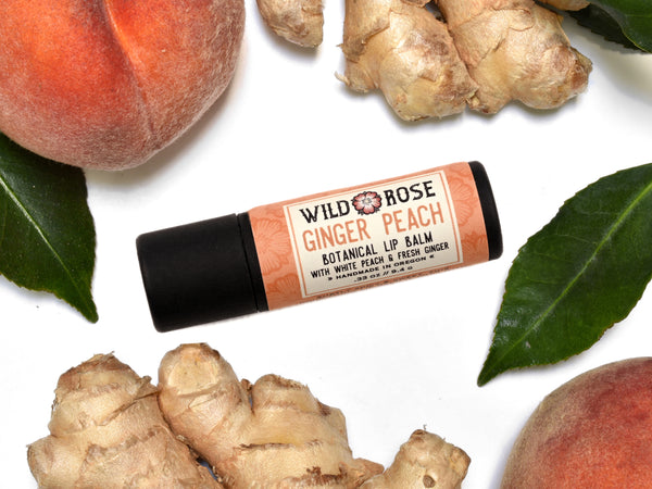 Ginger Peach Natural Lip Balm in a biodegradable paper tube. Peaches and ginger surround.