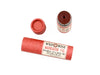 Wild Rose Mandarin Fig Botanical Lip & Cheek Tint in a biodegradable tube on a white background with fresh figs surrounding. The cap is removed revealing a dark red creamy tinted balm.