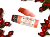 Wild Rose Roseberry Botanical Lip & Cheek Tint in a biodegradable tube, surrounded by rose hips on a white background. The cap is removed revealing a creamy soft red tint with product swatch above.