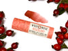 Wild Rose Roseberry Botanical Lip & Cheek Tint in a biodegradable tube, surrounded by rose hips on a white background. A product swatch is above.