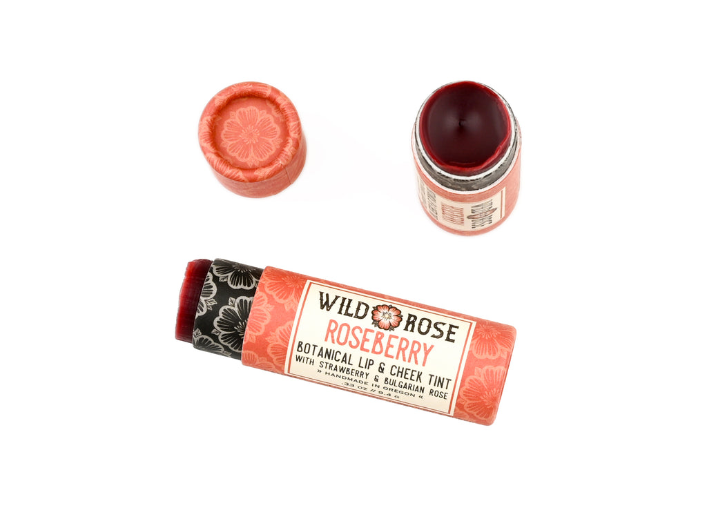 Wild Rose Roseberry Botanical Lip & Cheek Tint in a biodegradable tube on a white background. The cap is removed revealing a creamy soft red tint.