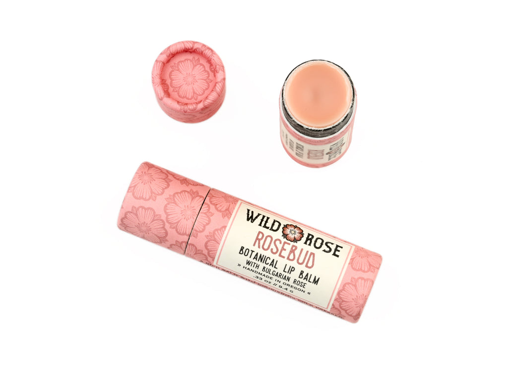 Wild Rose Rosebud Botanical Lip Balm in a biodegradable tube on a white background. The cap is removed revealing a creamy pink balm.