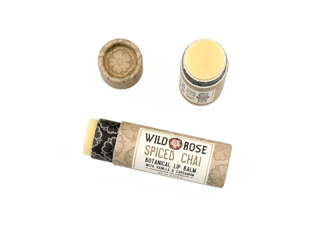 Wild Rose Spiced Chai Lip Balm in a biodegradable tube on a white background. The cap is off revealing a creamy white balm.