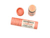 Wild Rose Strawberry Botanical Lip Balm in a biodegradable tube on a white background.. The cap is removed revealing a creamy pink balm.