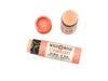 Wild Rose Strawberry Botanical Lip Balm in a biodegradable tube on a white background. The cap is removed revealing a creamy pink balm.