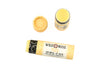 Wild Rose Yuzu Botanical Lip Balm shown with its yellow patterned cardboard tube, alongside the cap and an open tube displaying the yellow balm, on a white background.
