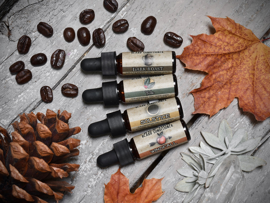 Three sets of Wild Man Beard Oil Conditioner - Holiday Sampler Set and pine cones on a wooden table.