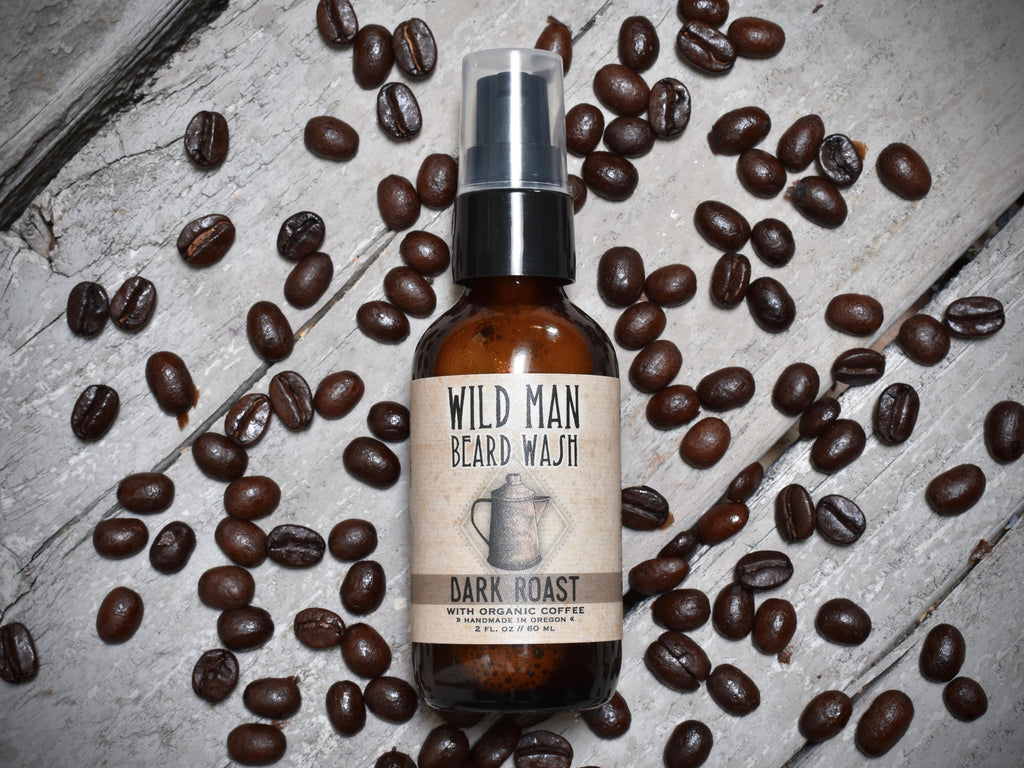 Wild Man Beard Wash 2oz amber glass bottle in Dark Roast scent. Coffee beans surround.
