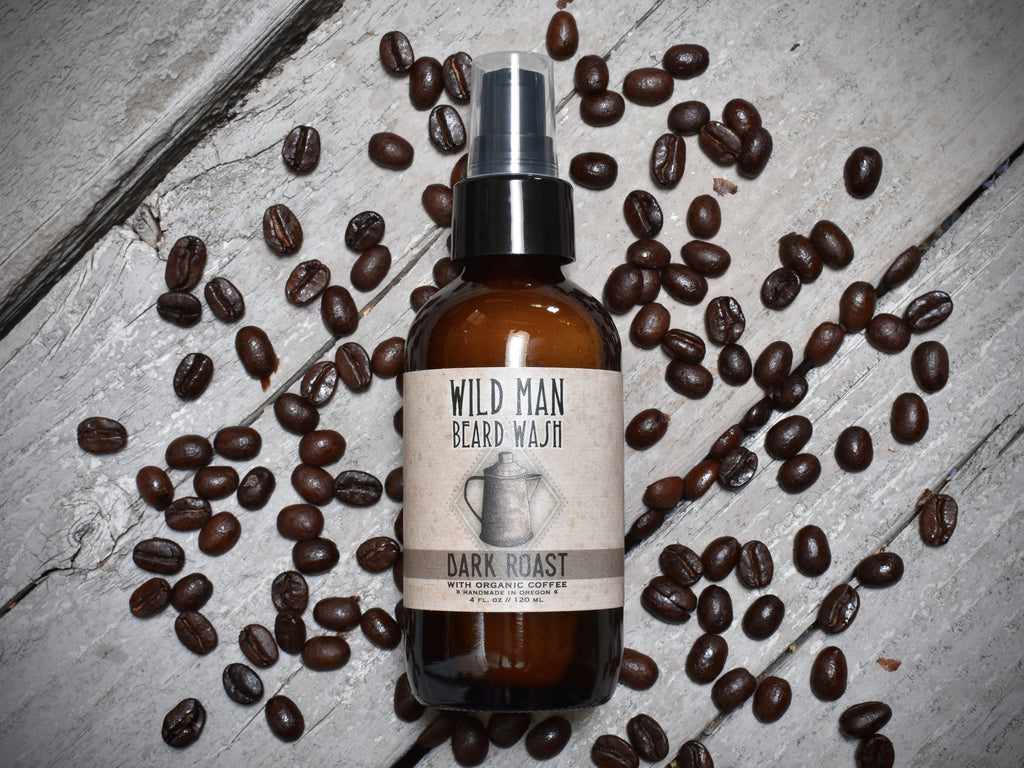 Wild Man Beard Wash 4oz amber glass bottle in Dark Roast scent. Coffee beans surround.