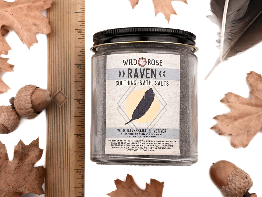 A jar containing Raven - Soothing Bath Salts, alongside a ruler, displaying a Pacific Northwest vibe by Wild Rose.