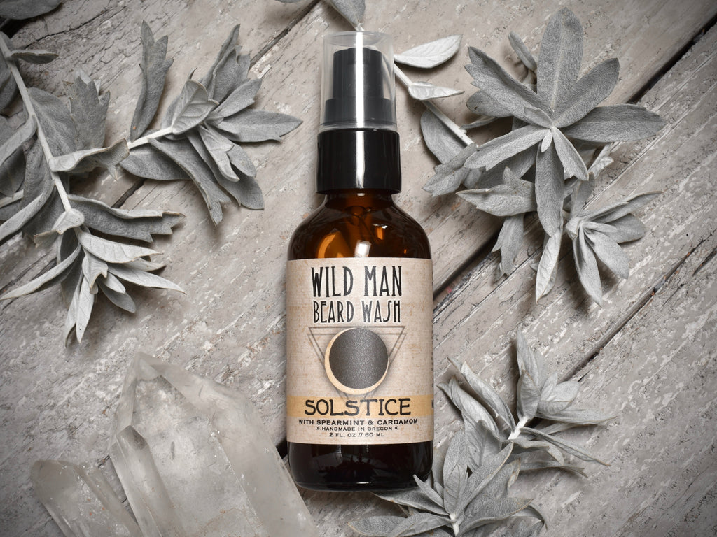 Wild Man Beard Wash 2oz amber glass bottle in Solstice scent. Mugwort leaves and quartz crystals surround.