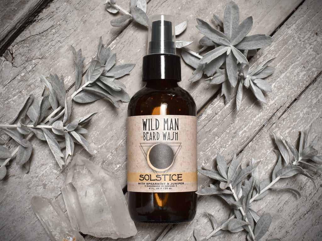 Wild Man Beard Wash 4oz amber glass bottle in Solstice scent. Mugwort leaves and quartz crystals surround.