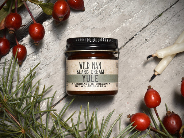Wild Man Beard Softening Cream 1oz amber glass jar in Yule scent. Rosehips and pine boughs surround.