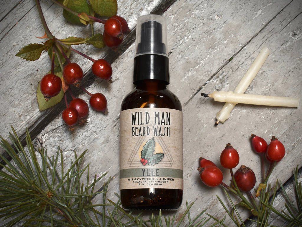 Wild Man Beard Wash 2oz amber glass bottle in Yule scent. Rosehips and pine boughs surround.